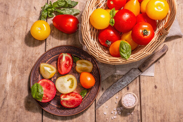 Fototapeta na wymiar Ripe assorted tomatoes with fresh basil in a wicker basket