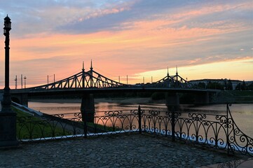 Urban landscape and a beautiful sunset in the evening on the river embankment with a bridge in the background. Copy space