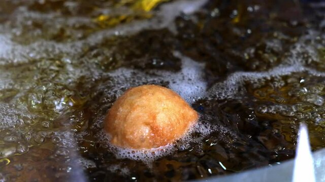 Close up of one lokma frying in heated oil, slow motion shot.
