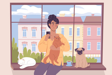 Cute girl sitting with her cats and dog by the window overlooking a street building