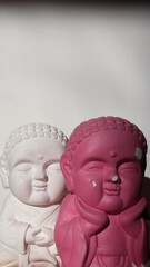Pink and white buddha statues with a white backgreound