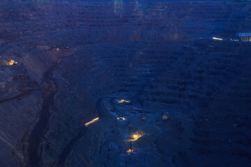 The process of ore extraction in the quarry at night. Heavy industry non-stop production of minerals.