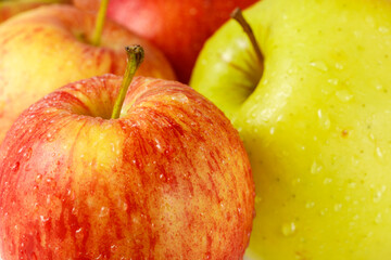 Red yellow ripe apple Royal Gala with water drops closeup on blurred fruits background.
