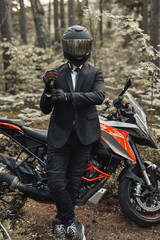 Naklejka premium Businessman biker with gloves and helmet posing in forest