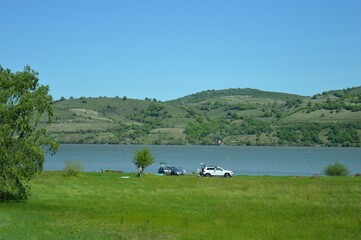 people with cars on a picnic by the river