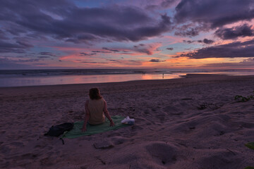 im sand sitzende person betrachtet sonnenuntergang am strand