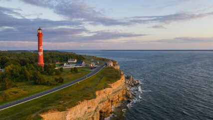 Sunset colored limestone cliff on Pakri peninsula, Estonia with the historic lighthouses and wind farm  on the background