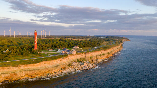 Sunset colored limestone cliff on Pakri peninsula, Estonia with the historic lighthouses and wind farm  on the background