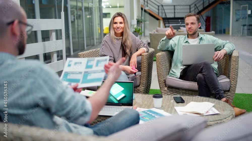 Wall mural startup business team of three sitting in office lobby and planning work. marketing manager explaini