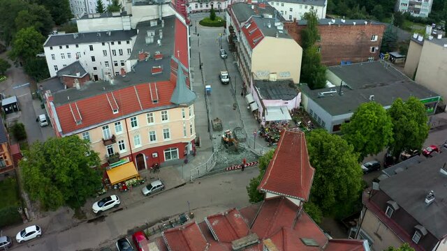 Aerial view of the street of the old city and a small excavator digging paving stones and loading it into a dump truck. Repair of the road and laying of new paving stones and a curb in the old city.