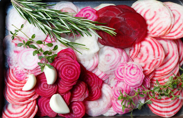 Various varieties of beets cut into thin slices. Chioggia beetroot, ordinary beetroot with green tops.