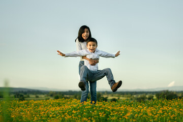 Hermana cargando a su hermano pequeño feliz en un campo de flores 