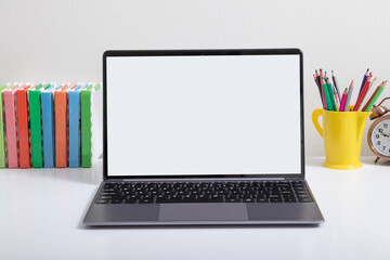 Open laptop mock-up at children's workplace with colored books and pencils. Back to school online learning concept