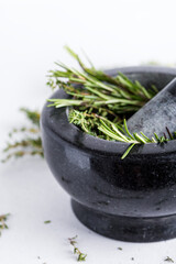 Bunch of fresh herbs in gray stone mortar with pestle