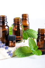 Collection of essential oils in amber bottles, mint leaves and lavender flowers