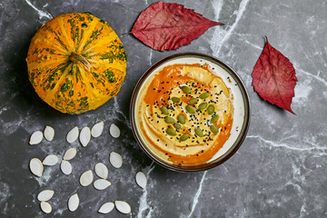 Creamy pumpkin soup with cream and seeds in a bowl