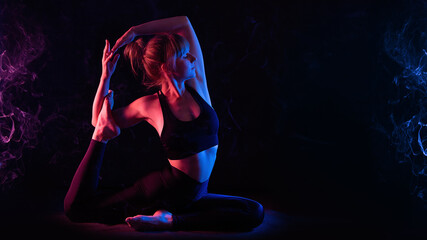 Yoga workout in neon light. Slim young woman yogi does yoga asana Eka pada raja kapotasana. Studio,...