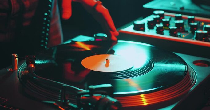 Deejay spinning vinyl musical record on turntable, playing disco during dj rave, close-up. Nightlife and music