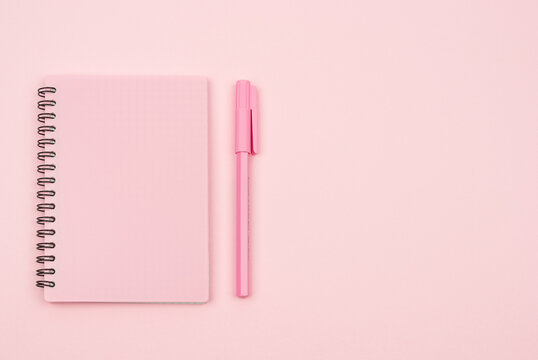 pink notebook and pink pen on a pink background