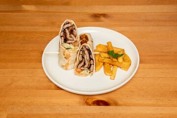 Burrito with a lot of beef and a little lettuce and tomato with grilled wheat tortilla and homemade chips
