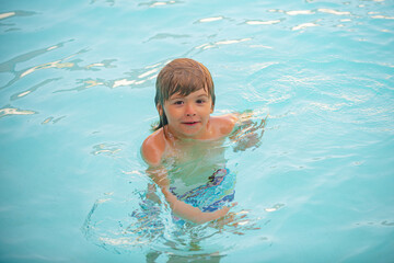 Summer child. Kid swimming in pool. Activities on pool. Summertime vacation concept.