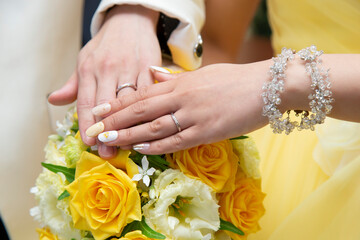 The bride and groom have their left hands on the bouquet