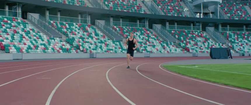 TRACKING Caucasian professional athlete practicing running on a large stadium. Shot with ARRI Alexa Mini with 2x anamorphic lens