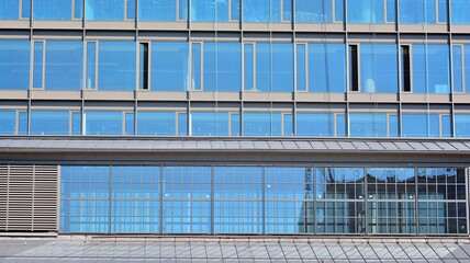 View of office building with glass wall under blue sky. Architecture details of business background.