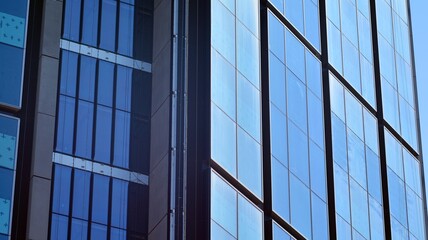 View of office building with glass wall under blue sky. Architecture details of business background.