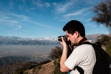 Portrait of young man taking pictures of mountain scenery on a sunny day.