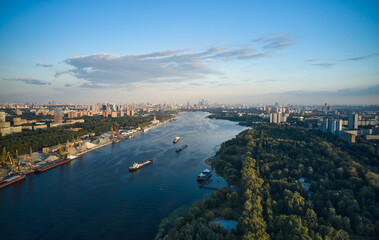 Fototapeta premium Aerial of ships and vessels are moving through the river in the city. Panoramic view of big city. River port and public park on the coastlines