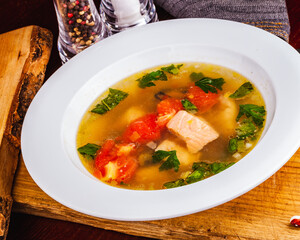 Fish soup with vegetables and salmon in white plate