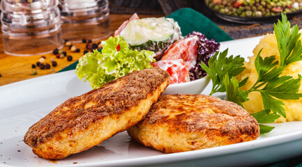 Chicken cutlets, mashed potatoes and vegetable salad on a white plate