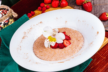 Oatmeal porridge with strawberries and raspberries in a white plate. Healthy food