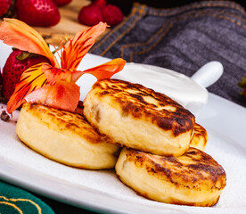 Breakfast. Cottage cheese pancakes, syrniki, curd fritters with fresh berries raspberry and strawberry, sour cream on white plate. Russian or Ukrainian cuisine.