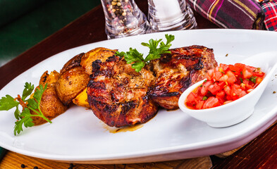 Grilled meat with baked potato and tomato on white plate
