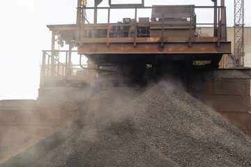 Iron ore pellets are piled from the conveyor belt into a heap. Falling of spherical lumps of...