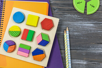 Wooden multicolored toys, blocks, notebooks, fractions on wooden table. Back to school, games for kindergarten, preschool education. - obrazy, fototapety, plakaty