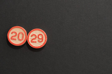 solid wood discs with the numbers 20 and 29 etched on both sides and highlighted in red-oranged and arranged on black background