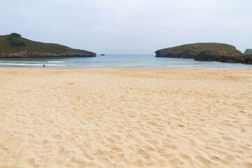 Beautiful beach in the town of Barro ( near Llanes ) early in the morning with a person walking, Asturias , Spain 