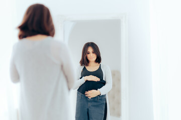 Fototapeta premium Happy Pregnant Woman Checking Maternity Jeans in the Mirror