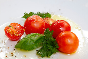 Cherry Tomatos and Basil with olicve oil on a White plate.