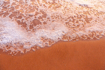 Sea waves and foam in sandy beach in evening.