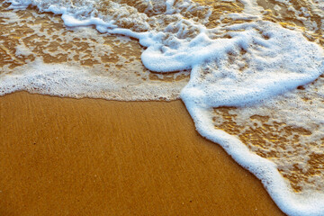 Sea waves and foam in sandy beach in evening.