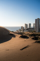 Dunes and sand with a city behind and the sea