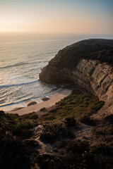 A beautiful beach between cliffs, with green shrubbery, at sunset