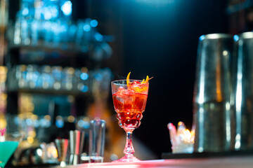 Bartender preparing tasty mixed alcoholic drink with ice cube in decorated cocktail glass on bar counter for customer in nightclub. Celebration party, nightlife business and alcohol addiction concept
