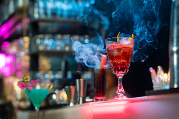 Bartender preparing tasty mixed alcoholic drink with ice cube in decorated cocktail glass on bar counter for customer in nightclub. Celebration party, nightlife business and alcohol addiction concept