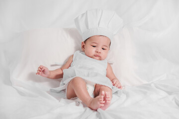 lovely baby bay in chef costume lying on bed