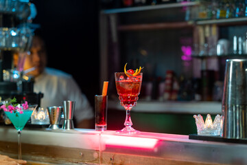 Bartender preparing tasty mixed alcoholic drink with ice cube in decorated cocktail glass on bar counter for customer in nightclub. Celebration party, nightlife business and alcohol addiction concept